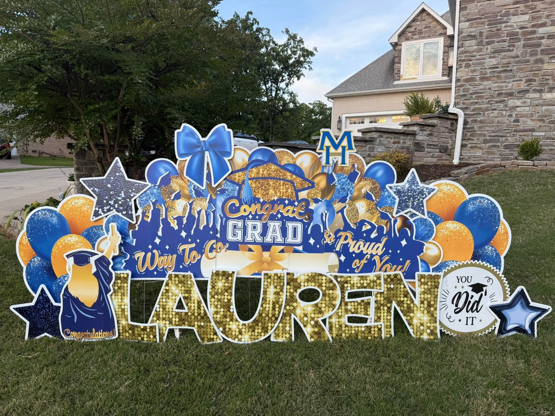 Graduation lawn display with blue, gold, and silver balloons and a large “Lauren” sign.