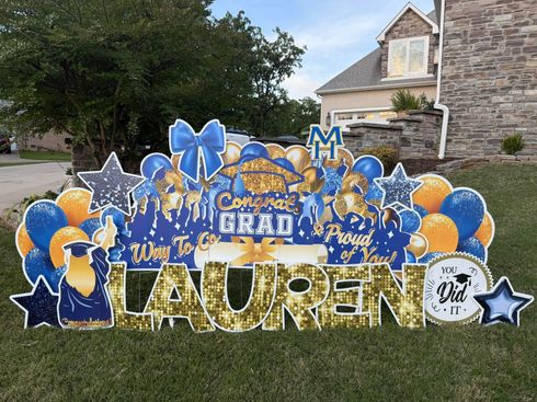 Blue and gold graduation lawn display with “Congrats Grad Lauren” and balloons outside a house
