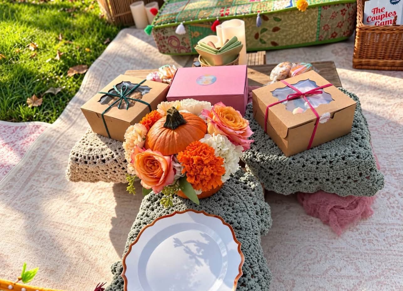 Gift boxes and orange flowers on crocheted blankets at a sunny outdoor picnic table