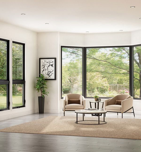 Modern living room with large windows, beige chairs, round table, and a rug overlooking greenery
