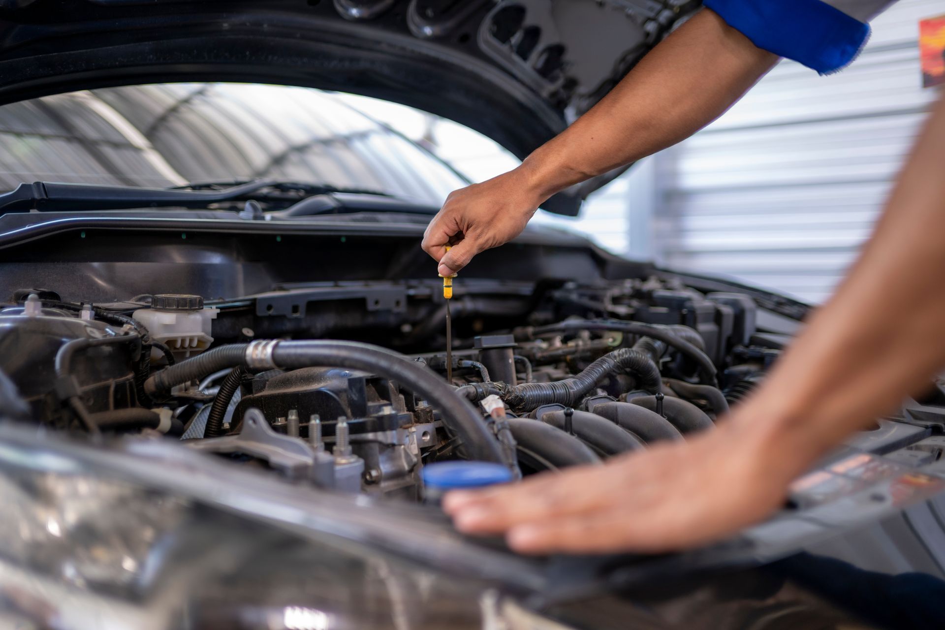 Mechanic checking car engine oil level with dipstick under the hood.