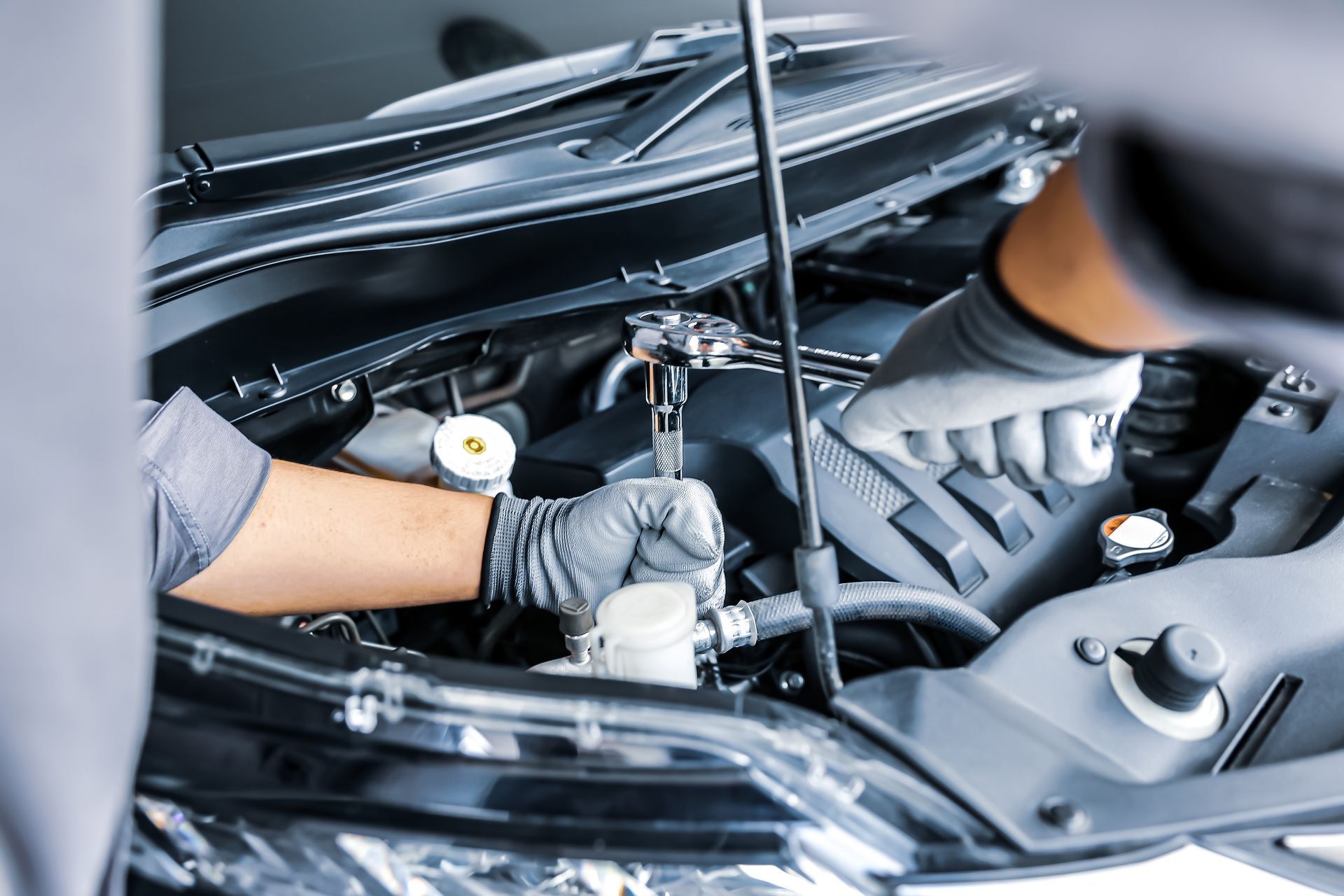 Mechanic working on a car engine, wearing gloves.