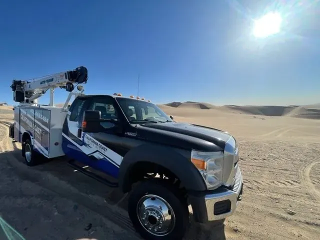 A utility truck with a boom lift parked in a desert landscape under a clear blue sky. | Kensington Motor Cars