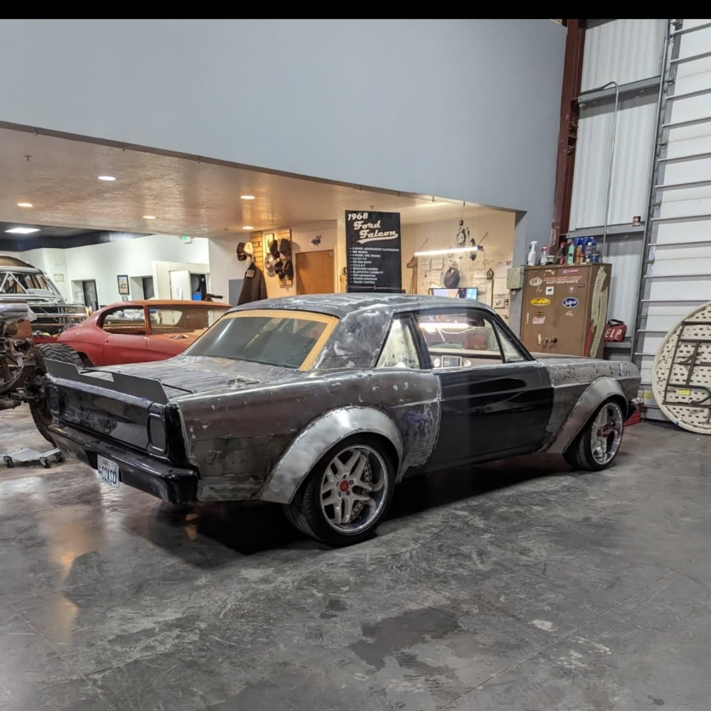 A truck is being built in a garage with a large tire.