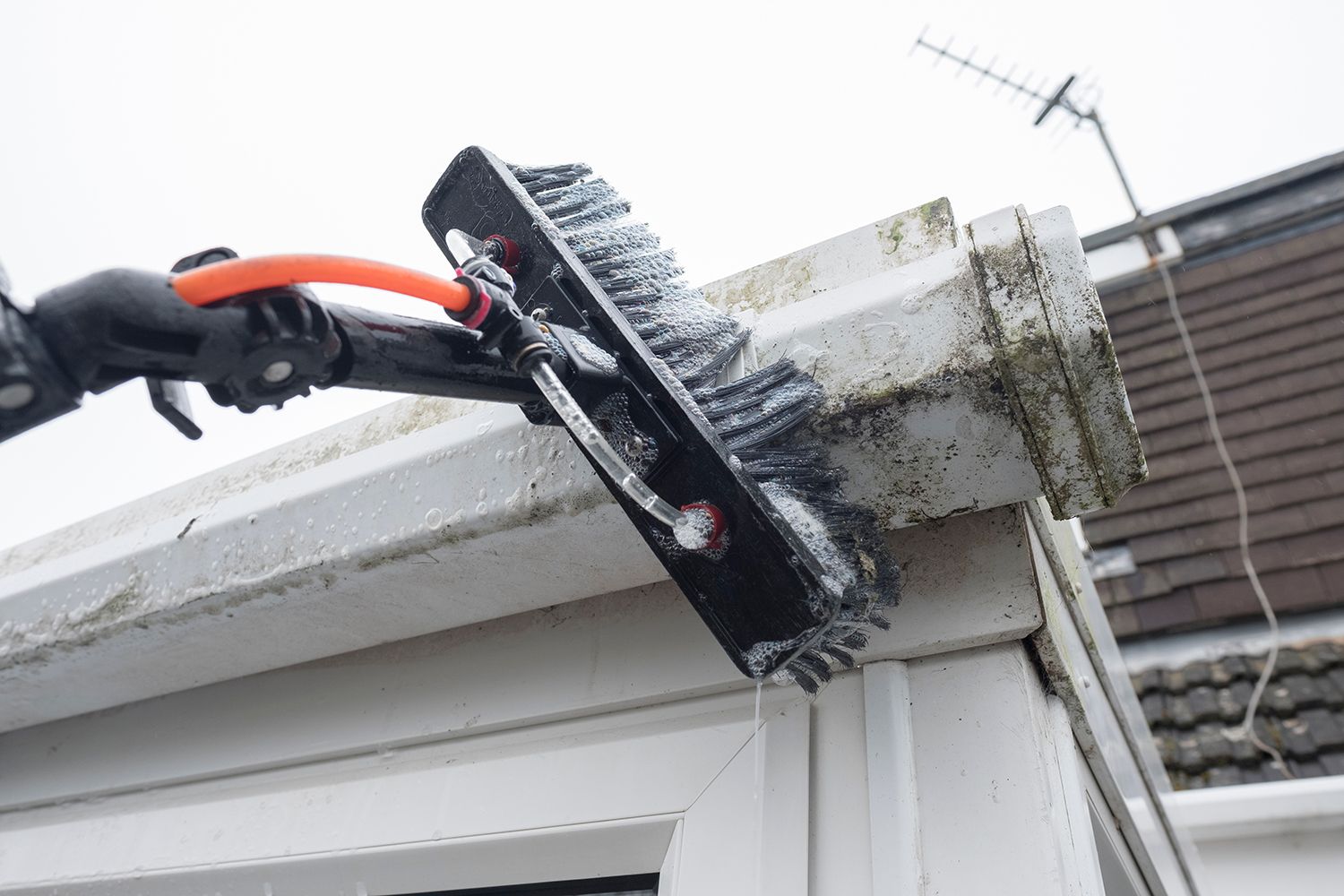 Person cleaning a white window frame with a brush on a house exterior Person cleaning a white window frame with a brush on a house exterior