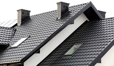 Slate-tiled roof with two chimneys and skylights on a house