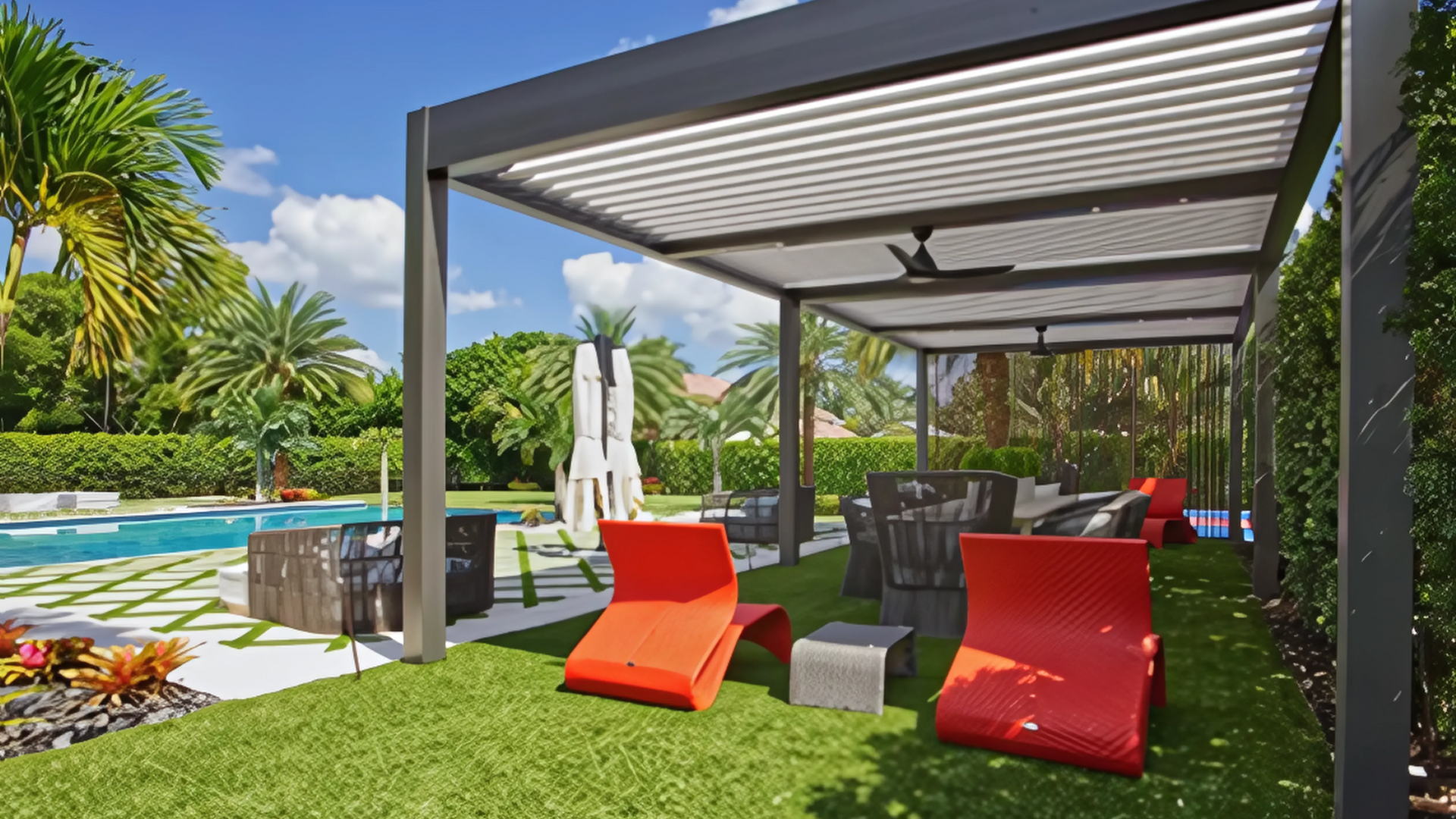 Outdoor patio with red lounge chairs under a modern pergola, near a pool and lush landscaping.