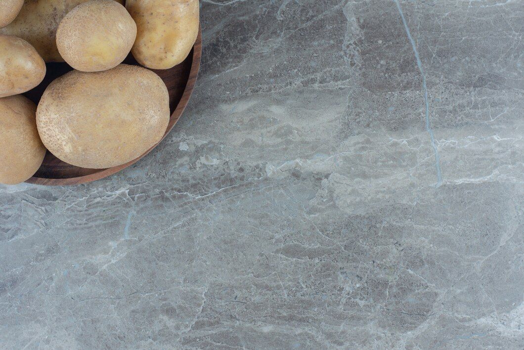A bowl of potatoes on a marble surface.