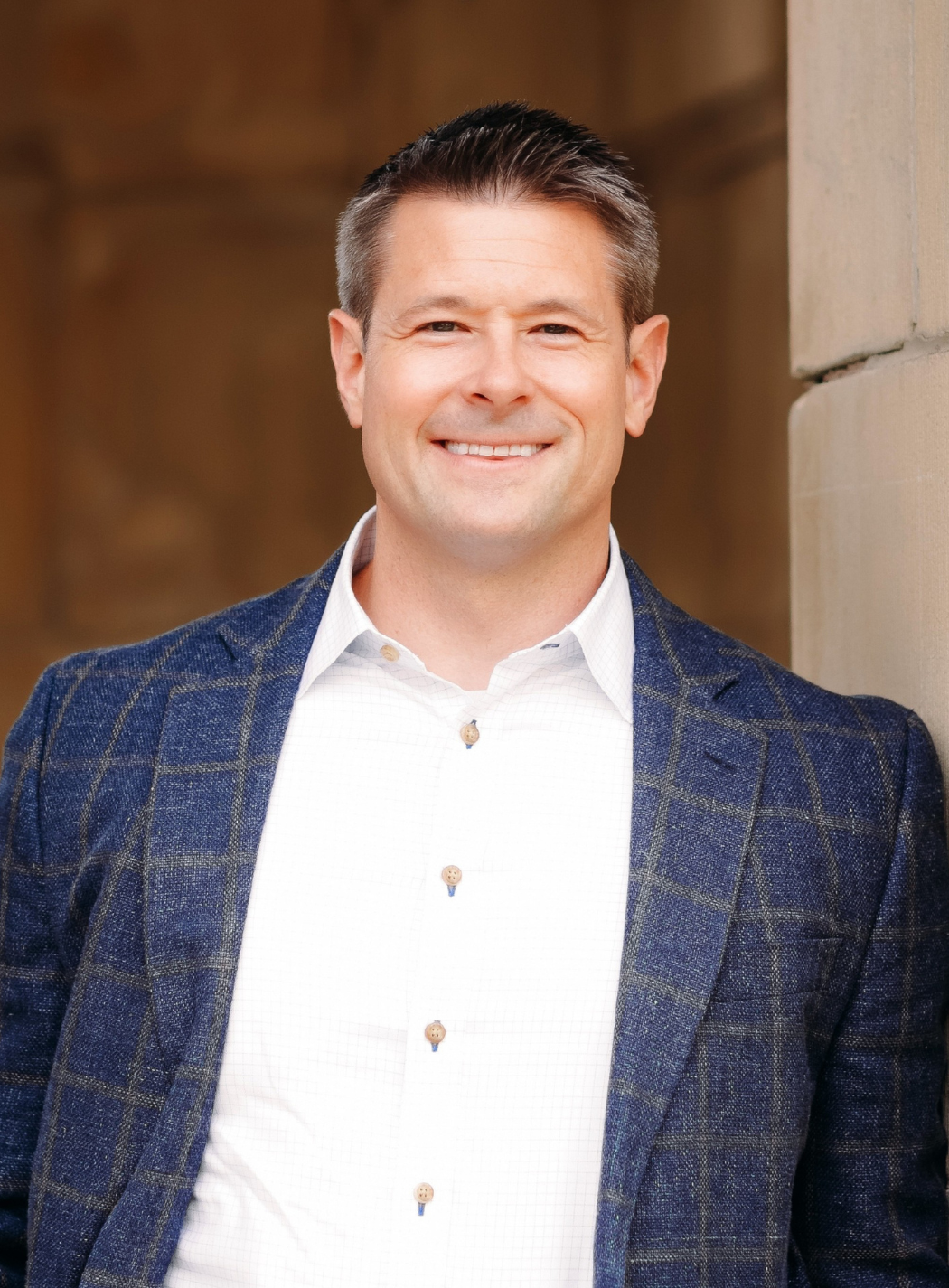 Jake Schlicht with hands clasped. Crouched against a dark gray background.