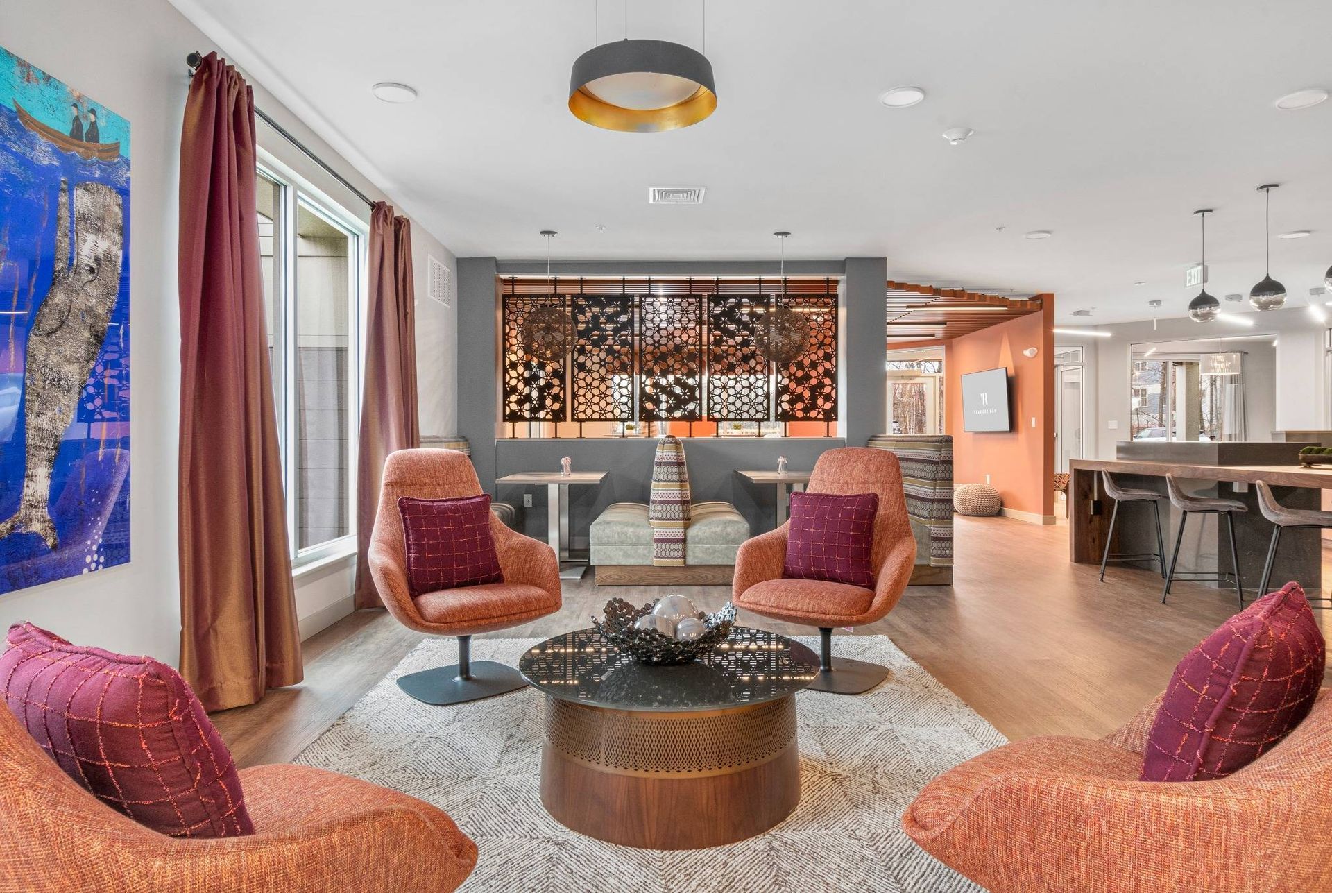 Modern lounge with pink chairs, round coffee table, and open seating area with warm lighting