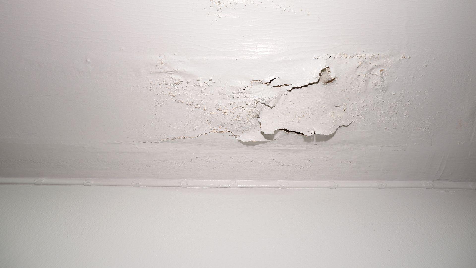 White ceiling with peeling paint and water damage near the top center