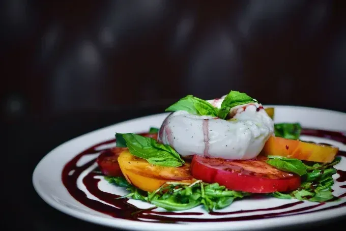 Gourmet plated dessert with white mousse, berry sauce, and fresh fruit garnish on a white plate
