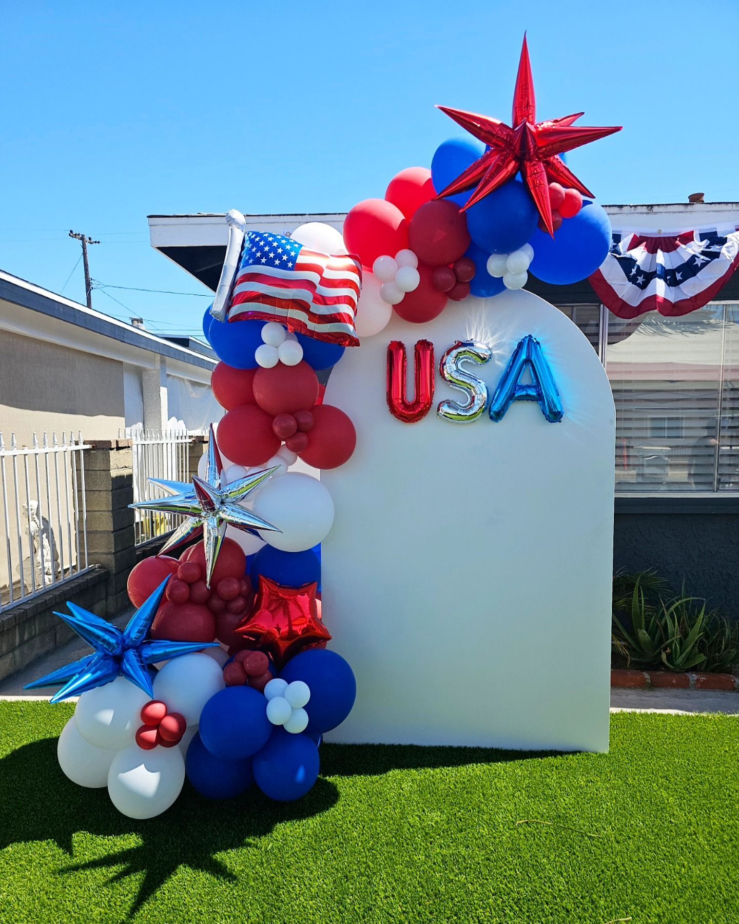 Patriotic red, white, and blue balloon display with “USA” letters outdoors on grass