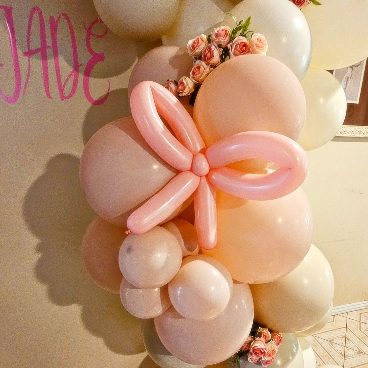 Pink and peach balloon flower display against a wall with floral accents