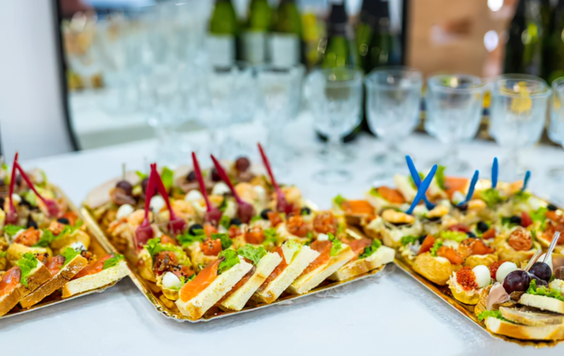 Colorful appetizer platters with skewers and olives on a white banquet table