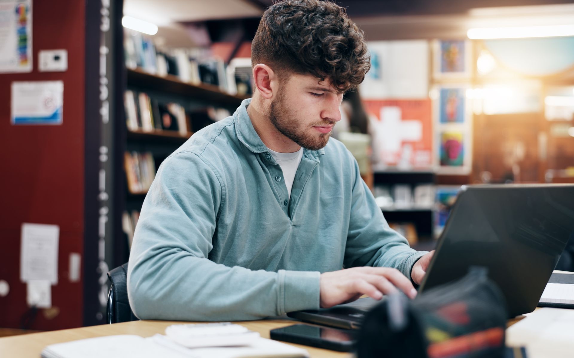 Man typing on laptop in library.