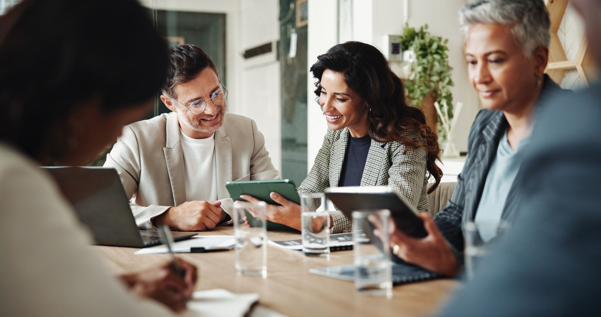 Business colleagues at a table reviewing data on tablets and laptop.