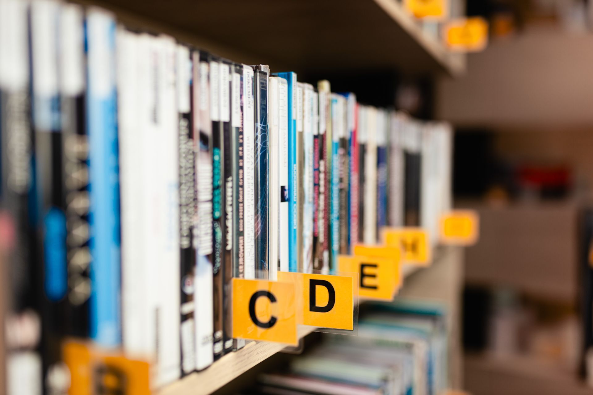 Books on library shelf with color-coded labels marked 