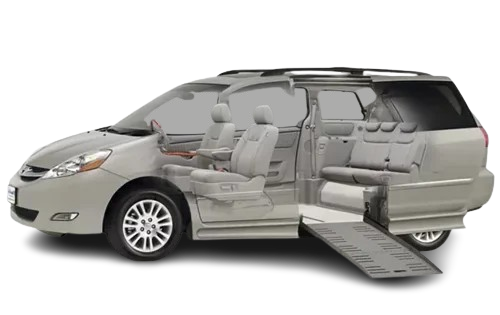 Silver wheelchair accessible minivan with ramp deployed. Interior seats visible.