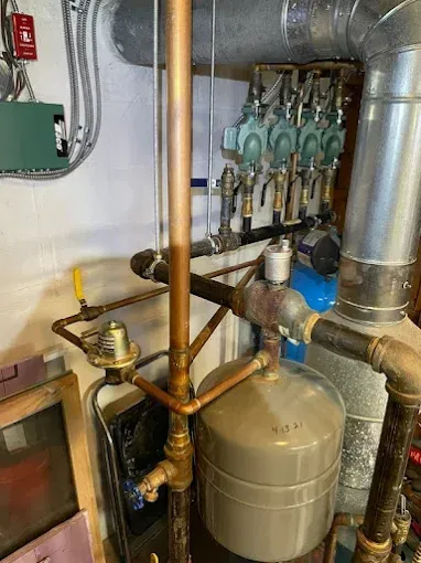 Copper pipes and valves of a boiler system, including a tank, pumps, and pressure relief components.