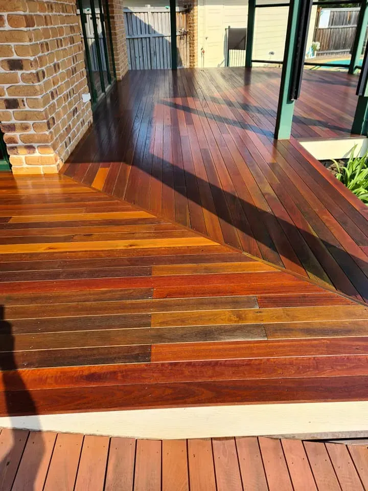 A Wooden Deck With a Brick Wall in the Background — Alan Aldridge Floor Sanding in Urraween, QLD