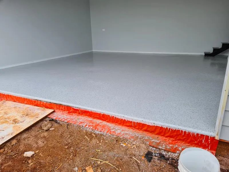 A Garage With a Concrete Floor and a Bucket on the Ground — Alan Aldridge Floor Sanding in Urraween, QLD