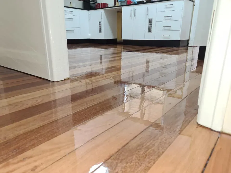 A Kitchen With a Wooden Floor and White Cabinets — Alan Aldridge Floor Sanding in Maryborough, QLD