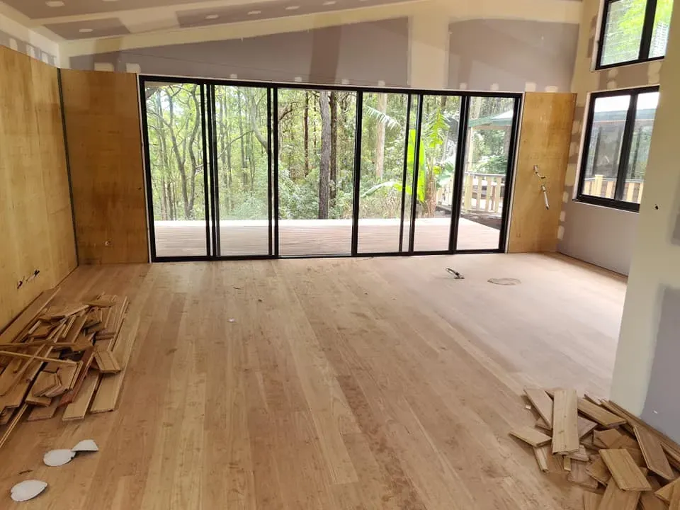An Empty Room With a Wooden Floor and Lots of Windows — Alan Aldridge Floor Sanding in Urraween, QLD