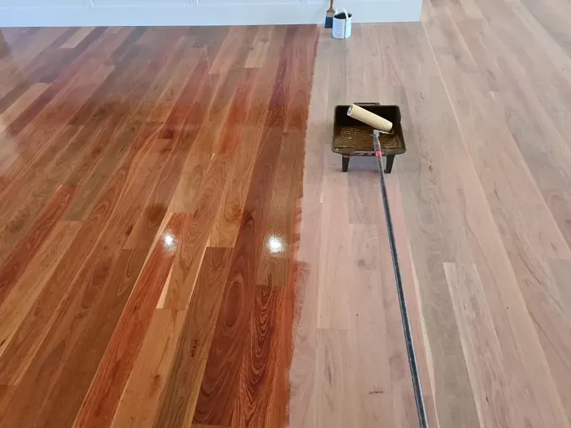 A Roller is Being Used to Paint a Wooden Floor — Alan Aldridge Floor Sanding in Urraween, QLD