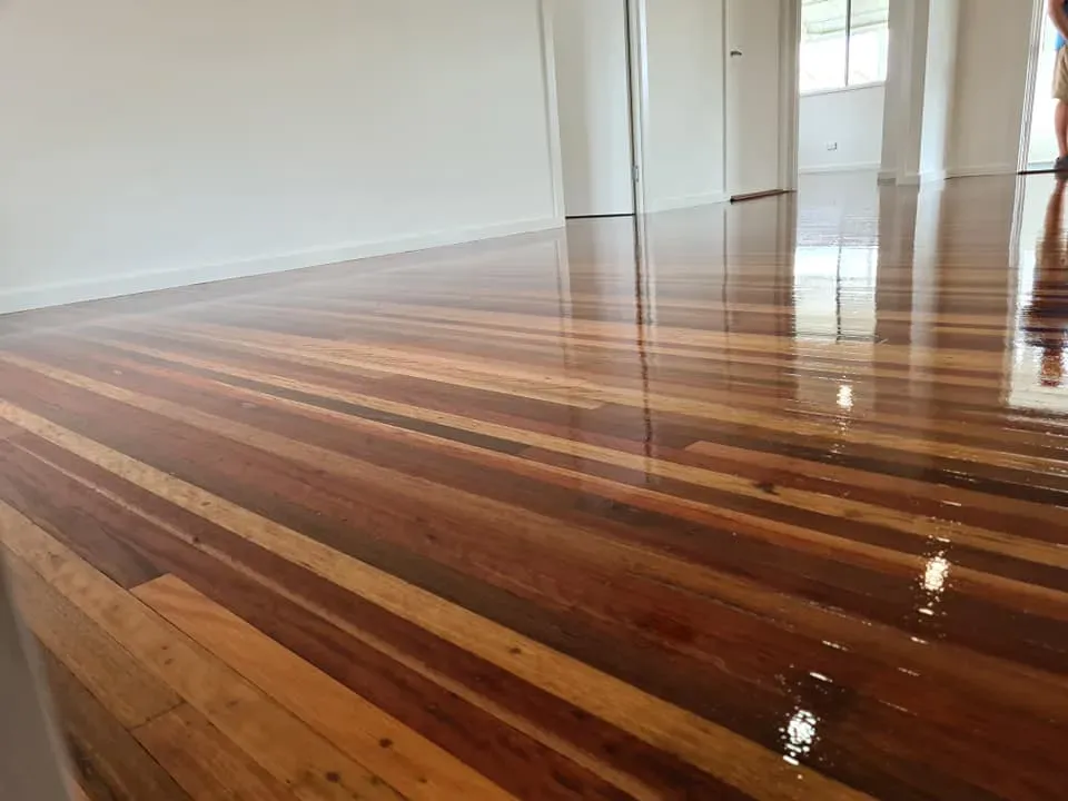 A Person is Standing on a Wooden Floor in a Room — Alan Aldridge Floor Sanding in Urraween, QLD