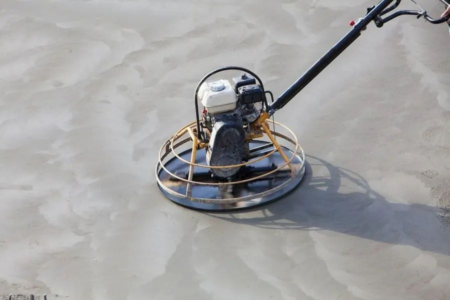 A Person is Using a Concrete Trowel on a Concrete Floor — Alan Aldridge Floor Sanding in Urraween, QLD