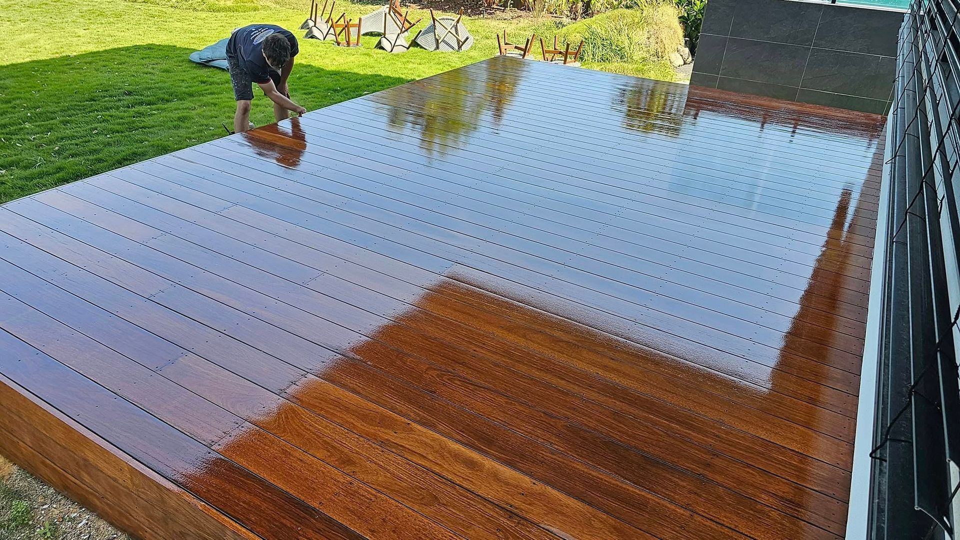 Person staining a wooden deck outdoors— Alan Aldridge Floor Sanding in Urraween, QLD