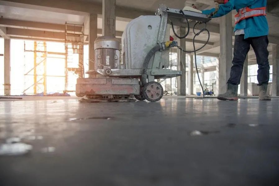 A Worker is Using a Machine to Cut Concrete in a Building Under Construction — Alan Aldridge Floor Sanding in Urraween, QLD
