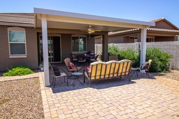 Covered patio with seating on a brick patio adjacent to a house.