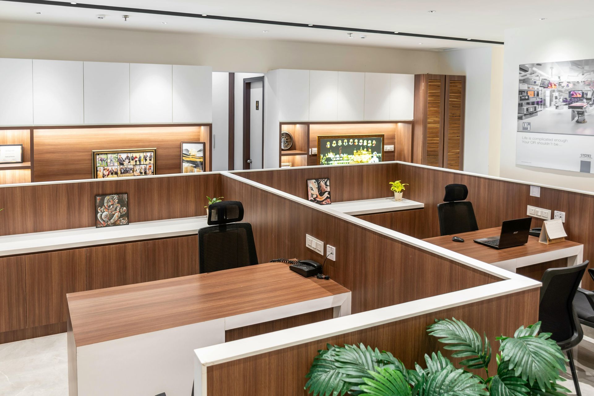 Modern office cubicles with wood and white accents, black chairs, and computers.