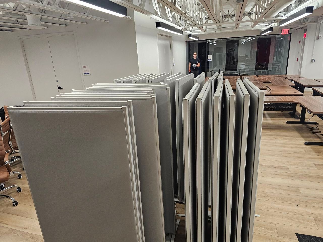 Stacked gray acoustic panels in an office workspace under bright ceiling lights