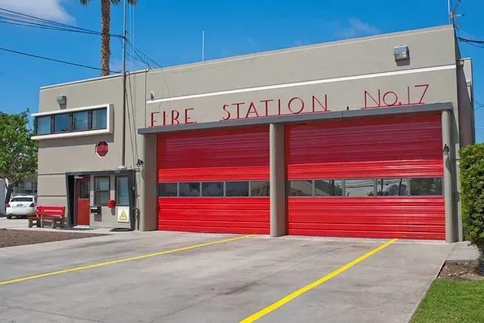 Fire Station No. 17 with bright red garage doors and a concrete apron under a blue sky