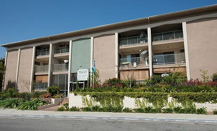 Two-story apartment building with balconies and a landscaped front walkway