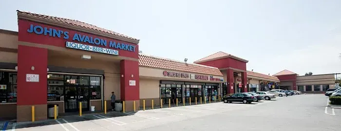 John’s Appliance storefront in a strip mall with red facade and parked cars outside