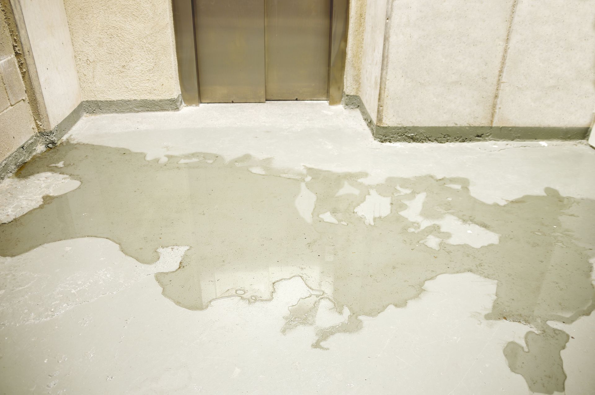 Floor with peeling, cracked coating in front of an elevator door inside a building