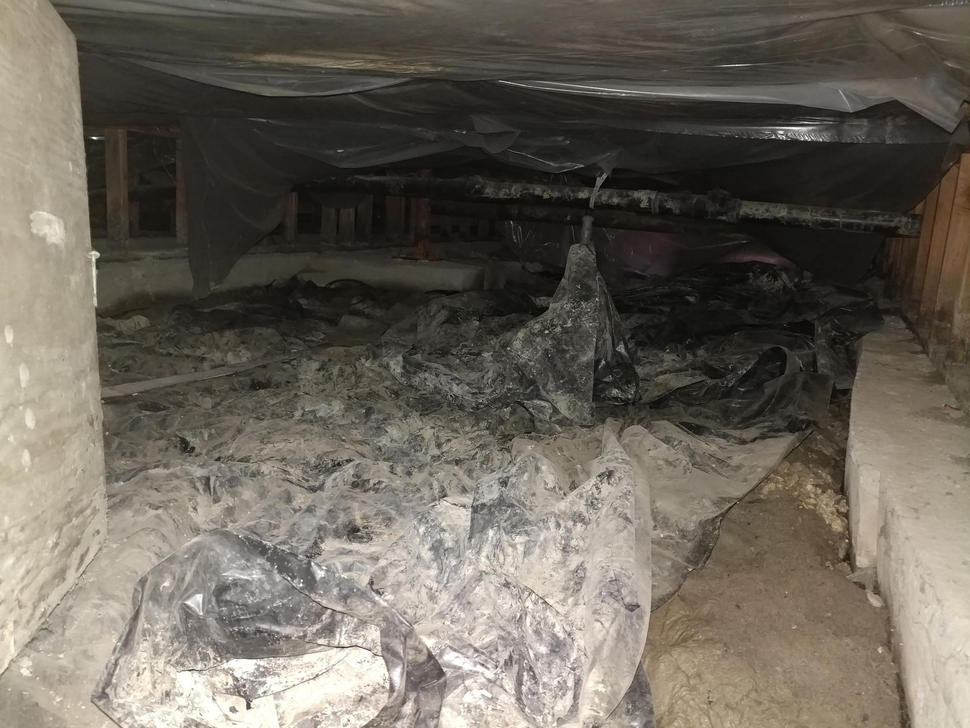 Charred crawlspace with burnt debris and blackened insulation under a building