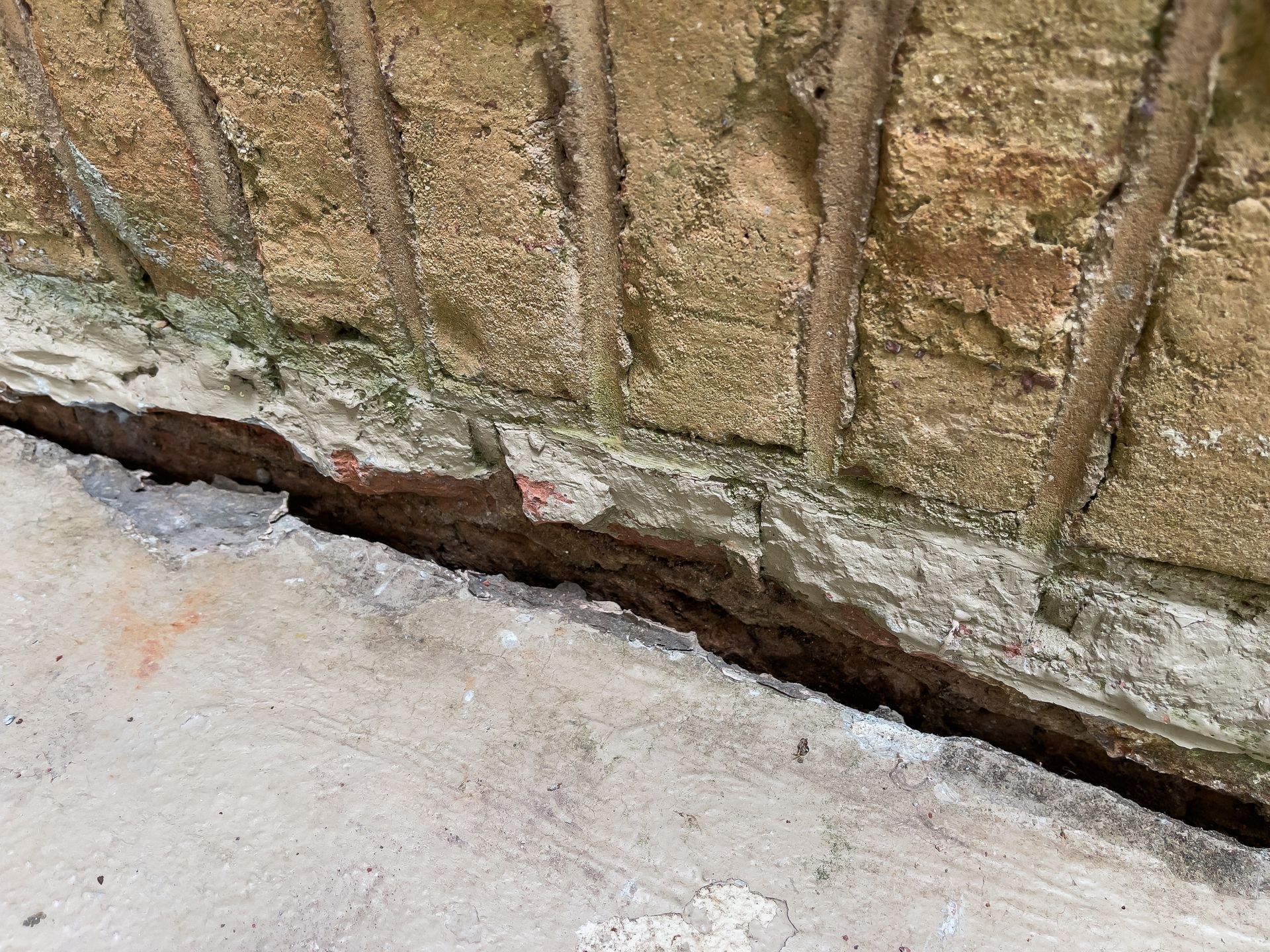 Flooded crawl space with insulated pipes and standing brown water beneath a house