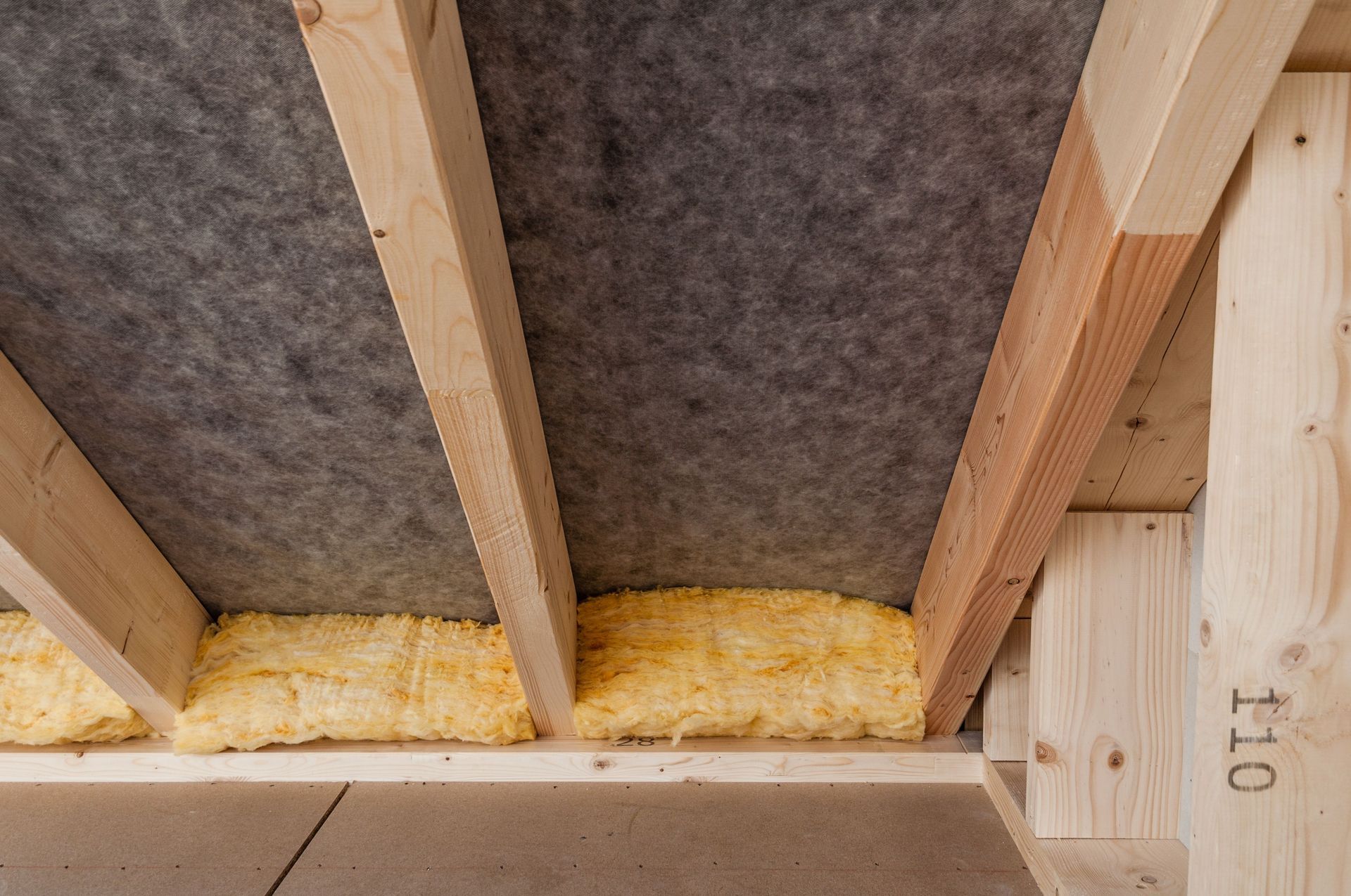 Flooded crawl space with insulated pipes and standing brown water beneath a house