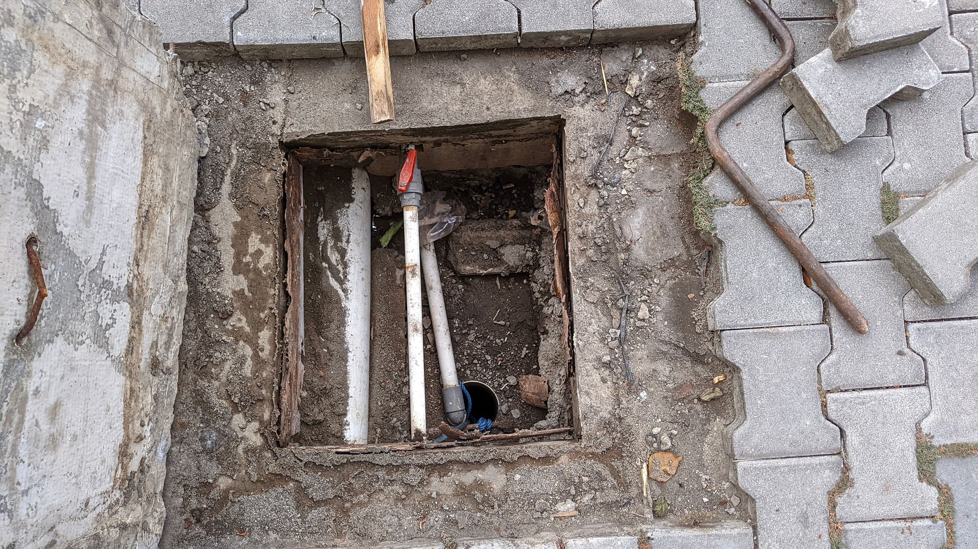 Flooded crawl space with insulated pipes and standing brown water beneath a house