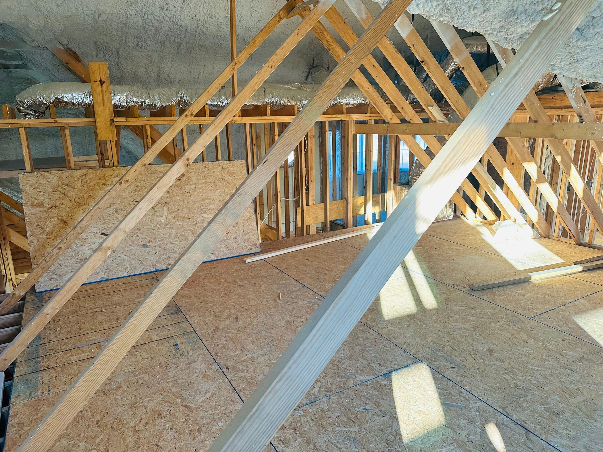 Flooded crawl space with insulated pipes and standing brown water beneath a house