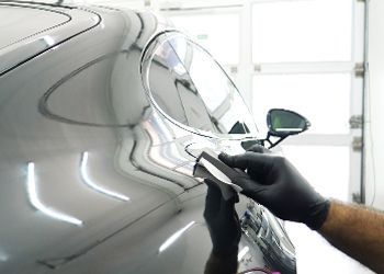 a person wearing black gloves is polishing a car in a garage .
