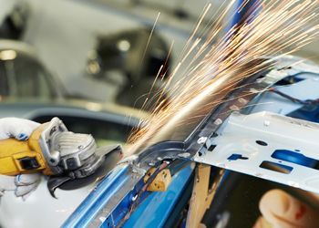 a person is grinding a piece of metal on a car .