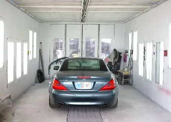 A car is parked in a paint booth in a garage.