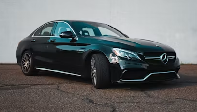Black Mercedes-Benz sedan parked on a street, front three-quarter view