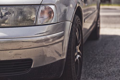 a silver car is parked on the side of the road .